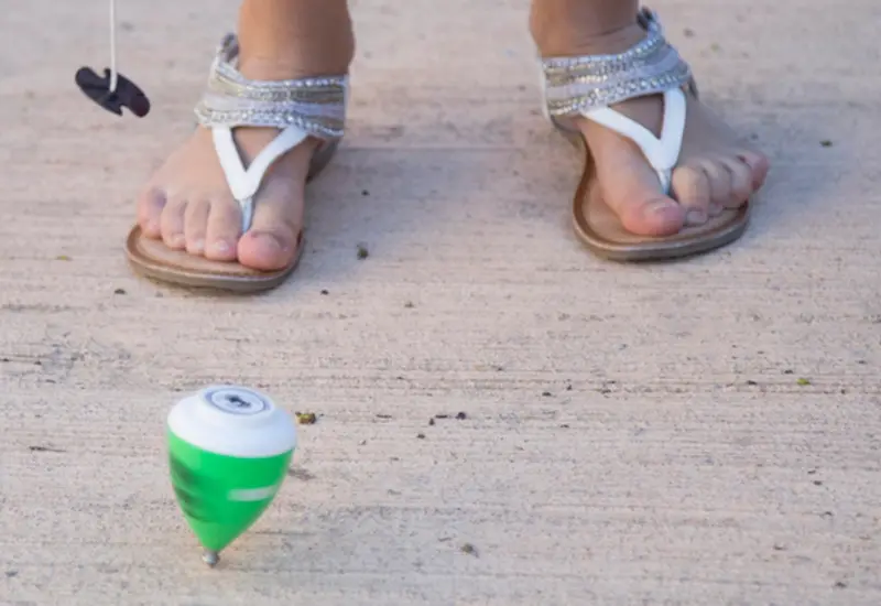 Niña jugando trompo
