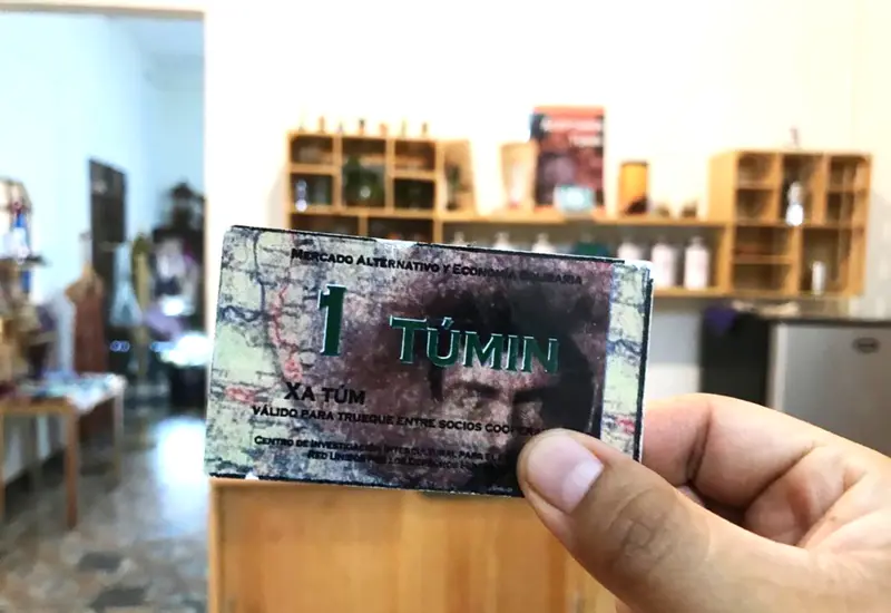 Billete de un tuním con cafetería de fondo.