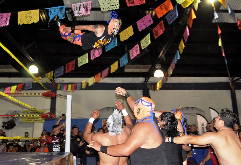 Luchador volando sobre sus oponentes