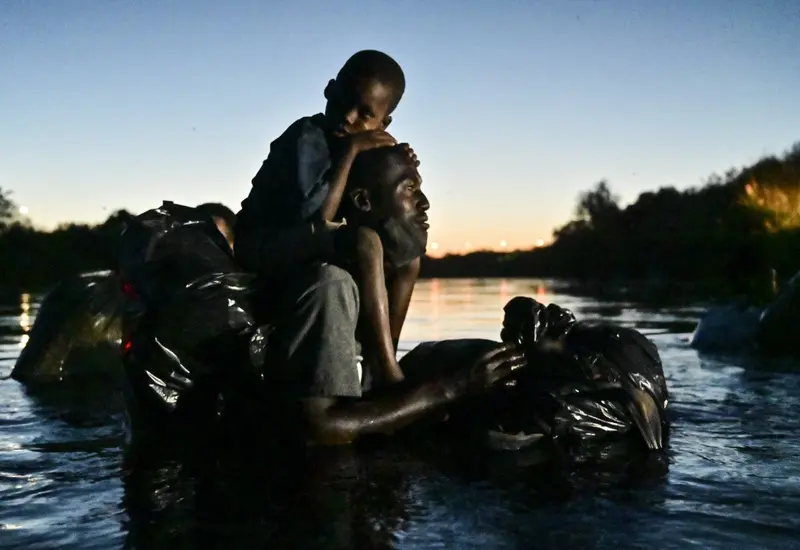 Migrantes haitianos cruzando un río