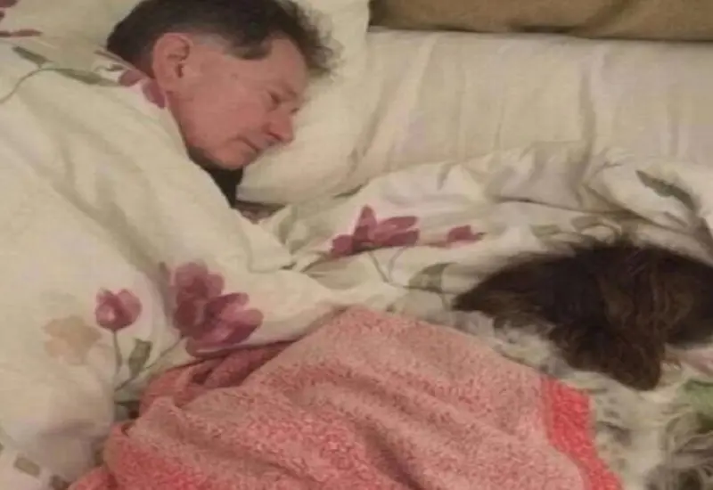 Señor durmiendo a un lado de su perro.