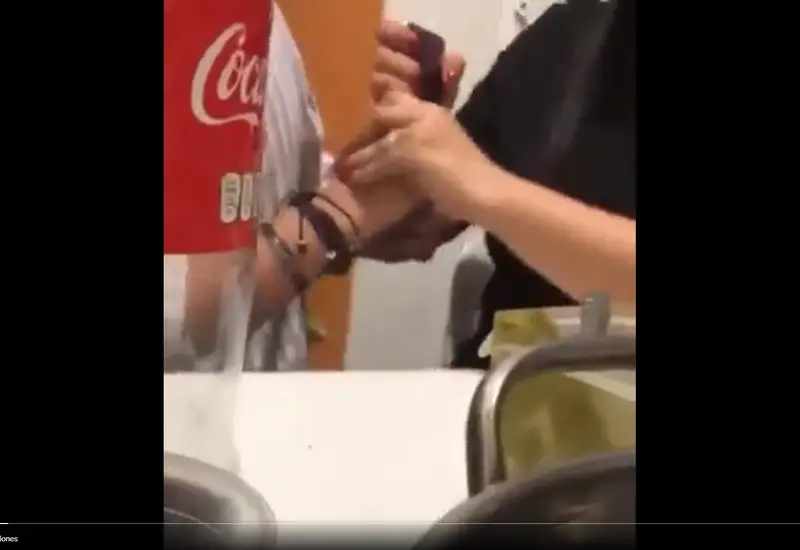 Mujer forcejea con su pareja para que le permita acceder a su teléfono celular.