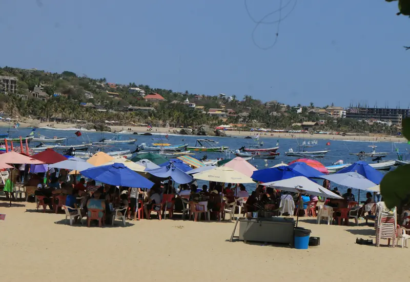 Una vista de la playa en Puerto Escondido llena de turistas durante la temporada alta, periodo en que aumentan las estafas por reservaciones falsas.