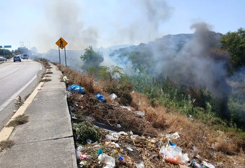 Un incendio consume los pastizales secos dentro del cauce del río Tehuantepec, generando una densa columna de humo visible en la zona.