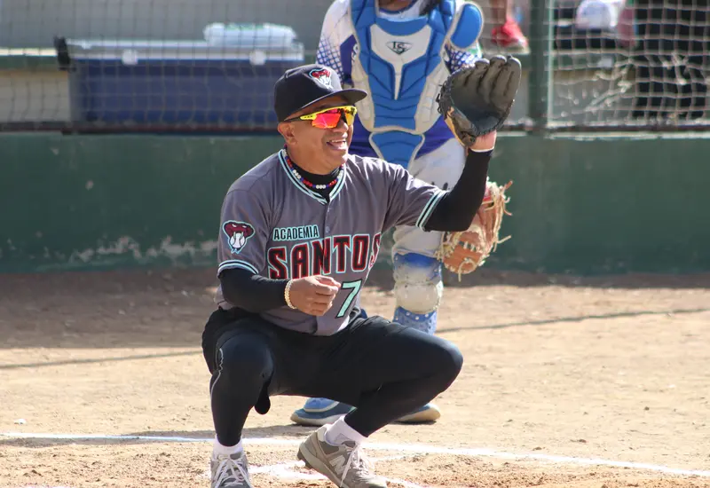 Jugadores del equipo Chivitos se preparan para su tradicional juego de béisbol de fin de año, alistando sus manoplas para el partido.
