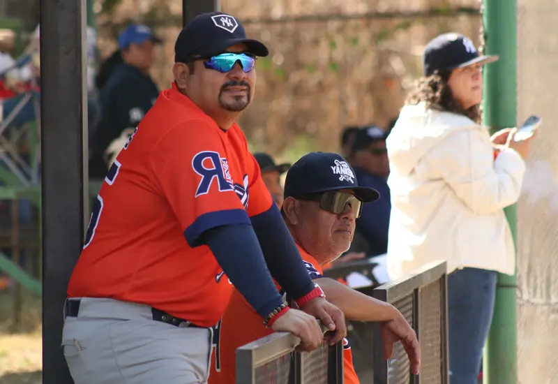 El mánager y un coach de los Yankees conversan en el dugout durante un partido de playoffs en busca del pase a la Serie Final.