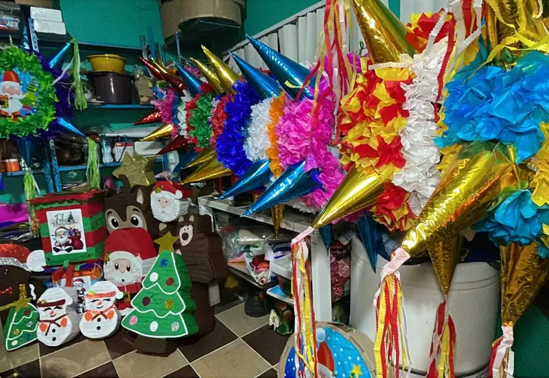 Una colorida variedad de piñatas tradicionales mexicanas colgadas en un puesto, mostrando el aumento de su demanda durante las fiestas de diciembre.