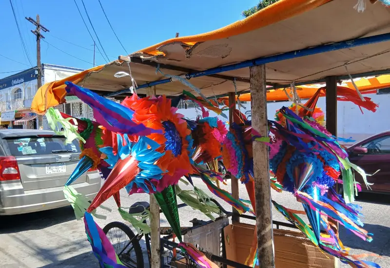 Una colorida exhibición de piñatas navideñas tradicionales, con sus característicos picos de estrella, colgadas en un puesto para su venta.