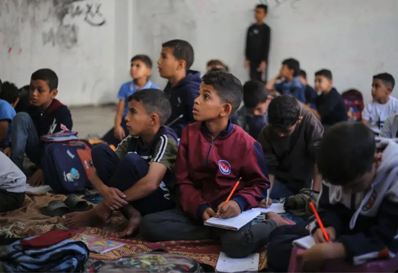 Los estudiantes toman lecciones en el suelo con el cuaderno en las rodillas. Foto: Afp
