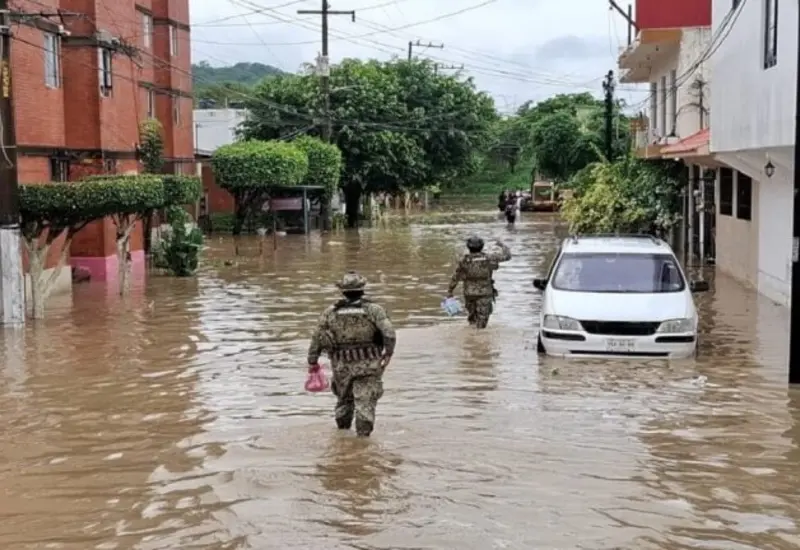 Una calle inundada con autos parcialmente cubiertos por el agua, ilustrando los daños materiales causados por las intensas lluvias en México.