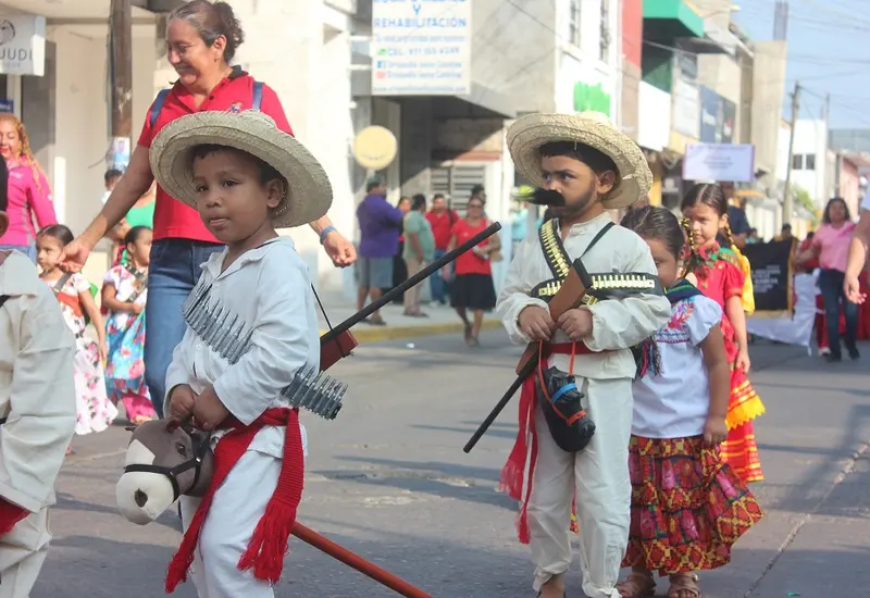 Un grupo de niñas y niños desfilan por la calle caracterizados con trajes de la época revolucionaria para conmemorar el aniversario.