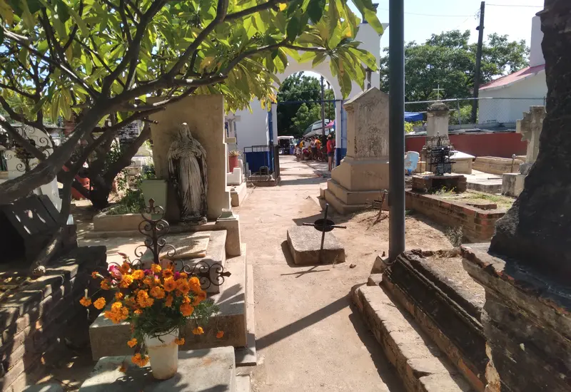 Familias y dolientes acuden a un camposanto para limpiar y adornar las tumbas de sus difuntos en la temporada de Día de Muertos.