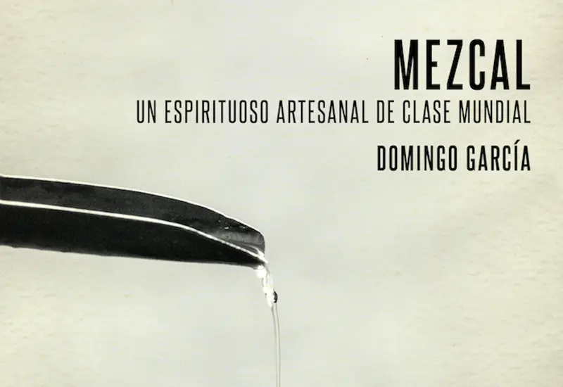 Una botella de mezcal artesanal junto a un vaso de veladora, ilustrando un artículo sobre los mitos y verdades de esta bebida tradicional mexicana.
