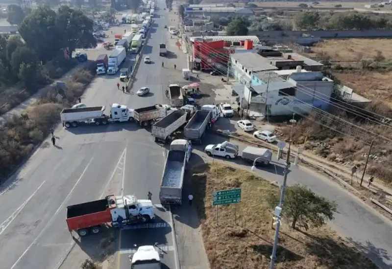 Un grupo de transportistas bloquea una carretera con sus camiones para protestar y exigir al gobierno mayor seguridad ante la crisis de asaltos.