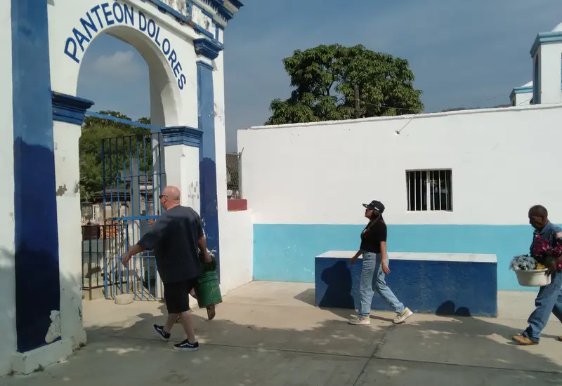 Una multitud de personas y familias caminan entre las tumbas de un panteón municipal, mostrando la gran afluencia de visitantes.