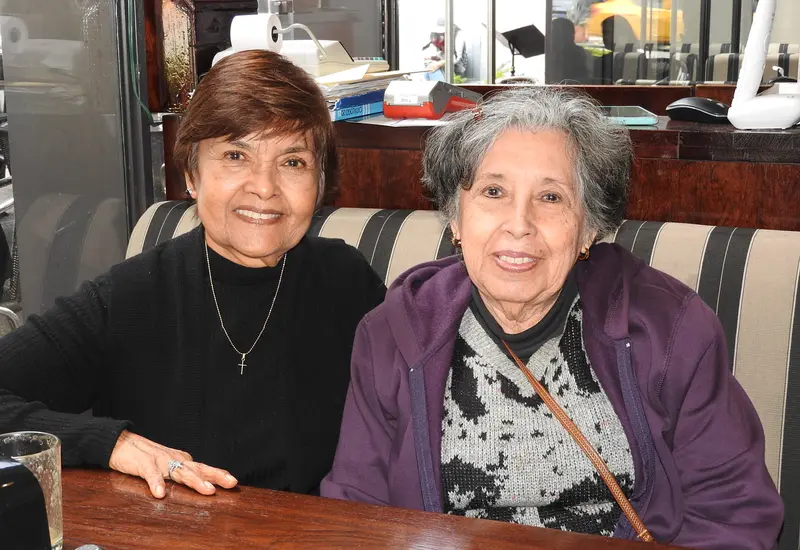 Un grupo de mujeres amigas sonríen y conversan alegremente mientras disfrutan de un desayuno en un ameno encuentro social.