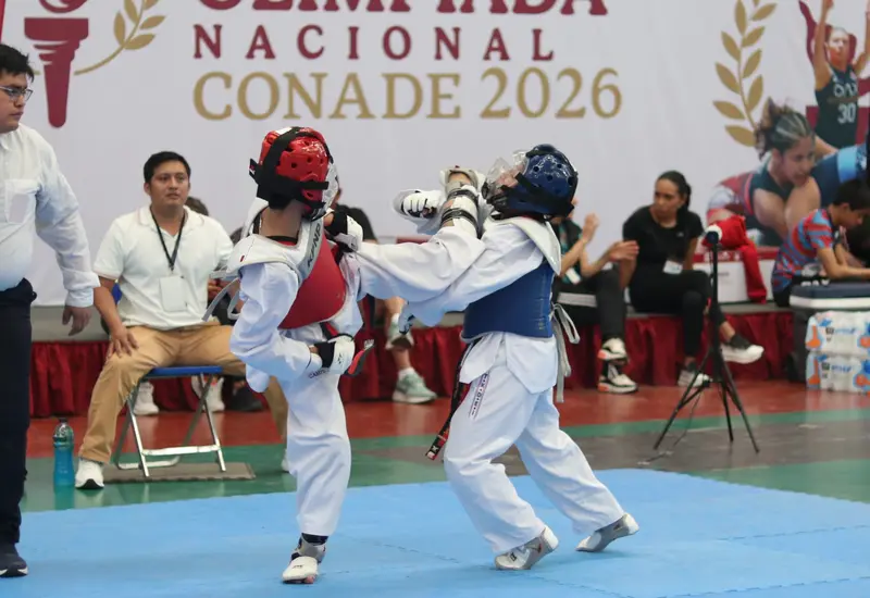 Dos atletas se enfrentan en un duro combate de taekwondo durante el torneo estatal, demostrando su habilidad y esfuerzo en la competencia.