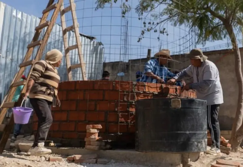 Miembros de la organización Flor y Canto trabajan en la construcción de un sistema de captación de agua de lluvia en una escuela de Zaachila.