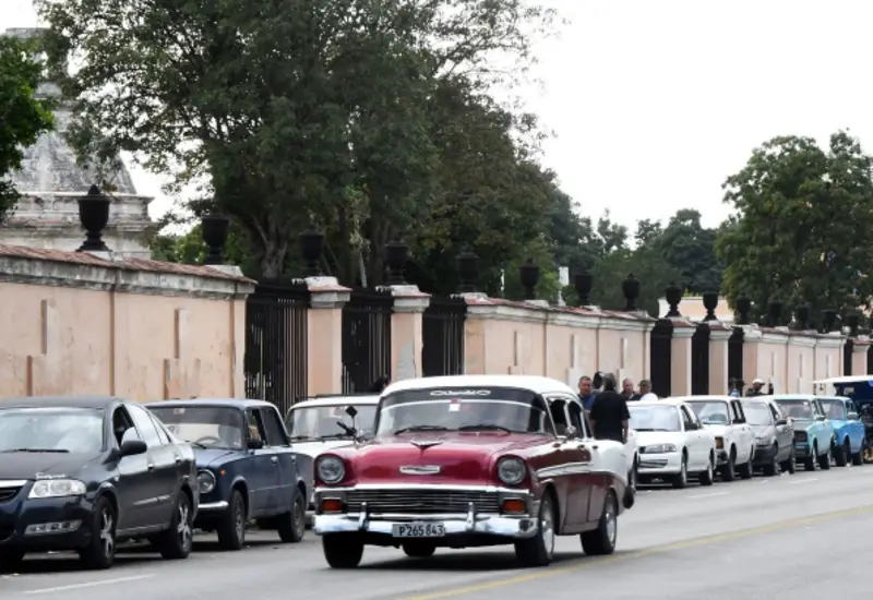 Larga fila de vehículos esperando para cargar combustible en Cuba, ilustrando la escasez y las fallas de transporte advertidas por la embajada de EU.