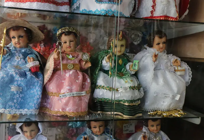 Varias figuras del Niño Dios vestidas con diferentes trajes, representando la tradición mexicana de elegir una madrina para su cuidado anual.