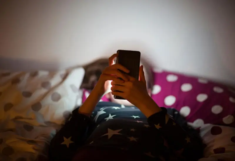 Un joven absorto en la pantalla de su teléfono, representando la falta de control sobre el tiempo de uso que afecta a casi la mitad de los menores.