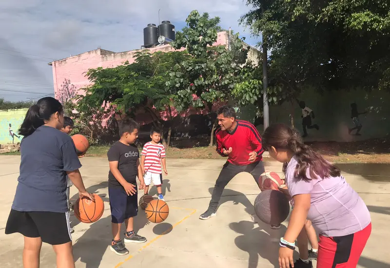 Jóvenes participantes aprenden los fundamentos básicos del basquetbol como parte de las actividades del curso de verano en San Agustín de las Juntas.