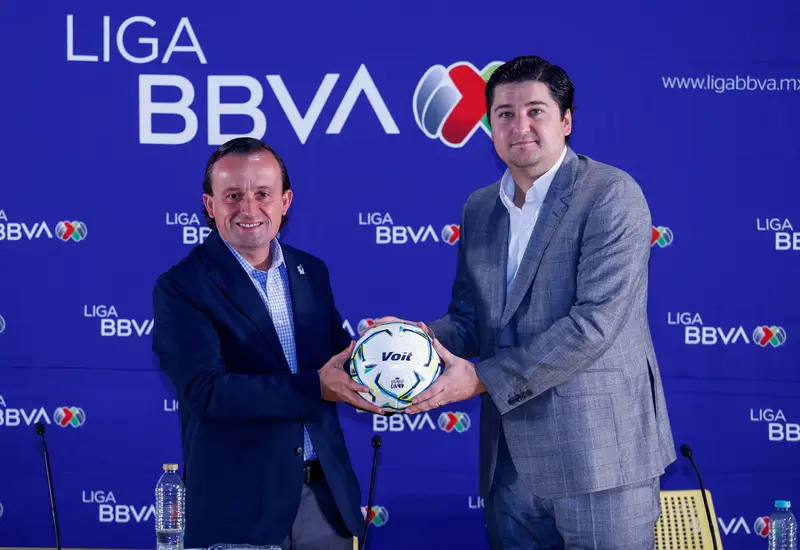 Mikel Arriola, presidente de la Liga MX, entrega simbólicamente un balón de fútbol al nuevo directivo Francisco Iturbide durante el cambio de mando.