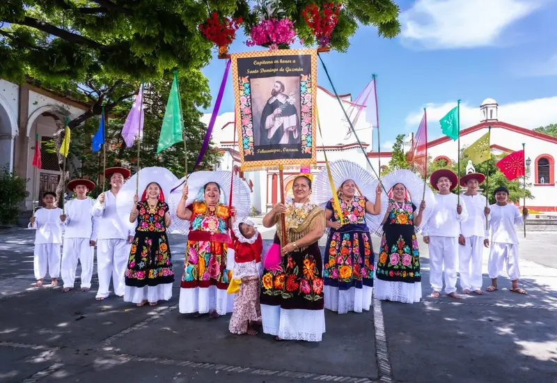 Artistas presentan el bailable 'Sandunga, mamá por Dios' en el marco del festival de la Guelaguetza, luciendo trajes típicos regionales.