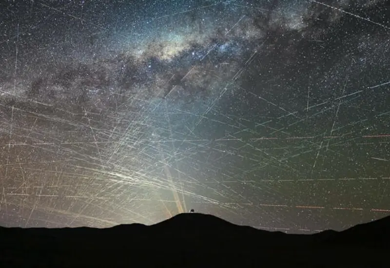 Cielo nocturno estrellado interrumpido por las estelas de luz de satélites comerciales, una amenaza que altera la investigación astronómica de los científicos.