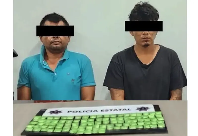 Los dos sujetos detenidos son presentados ante la cámara junto a las 100 dosis de droga que les fueron encontradas.