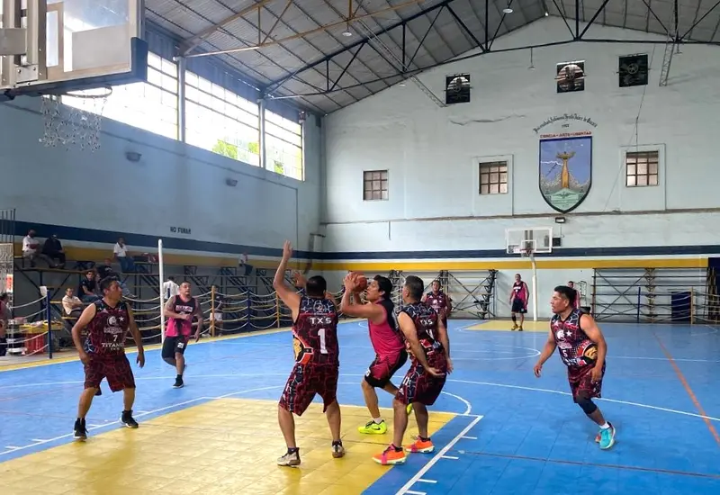Escena de acción del partido de básquetbol de veteranos, donde el equipo Grúas Gale avanzó a semifinales en el Gimnasio Universitario del Centro.