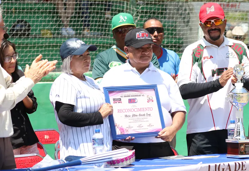 El presidente de la Liga Vasconcelos entrega un reconocimiento a Lety Acevedo durante la ceremonia inaugural del 85º torneo deportivo.