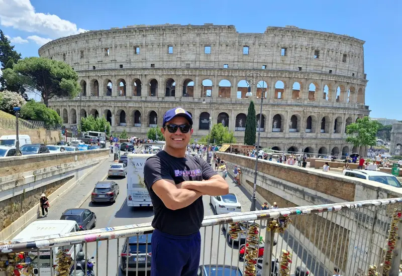 El luchador oaxaqueño Paul Lara, conocido como Rasputín, posa de pie frente al histórico Coliseo Romano en Italia.