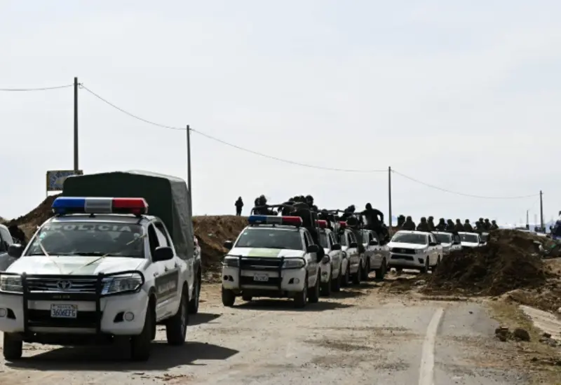 Militares y policías bolivianos retiran barricadas de una carretera para despejar los bloqueos tras la declaración del estado de excepción en el país.