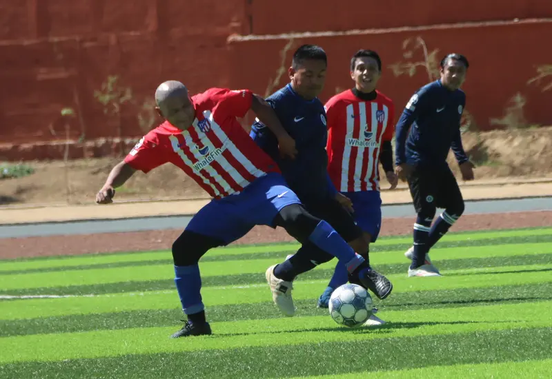 Jugadores de Novasistem y Zoé disputan el balón durante un intenso partido de la quinta jornada de la liga Premier de fútbol.