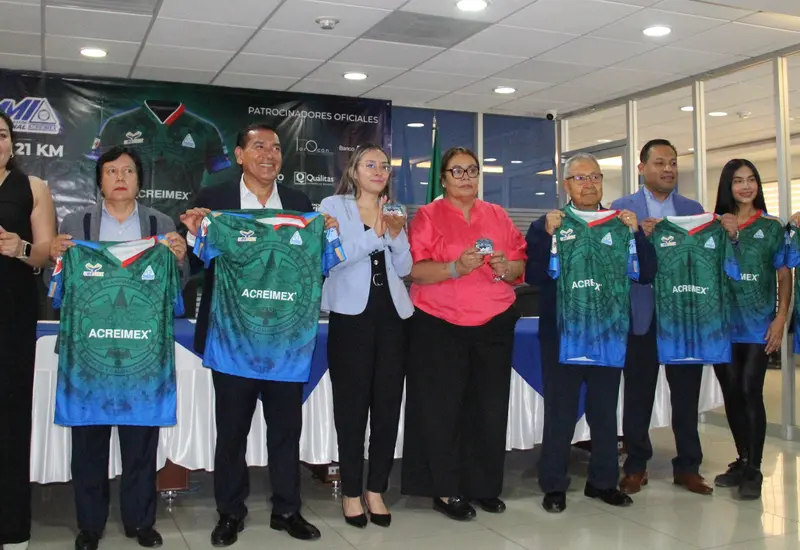 Las playeras y medallas oficiales para la novena edición del Medio Maratón Acreimex 2026 son exhibidas durante el evento de presentación.