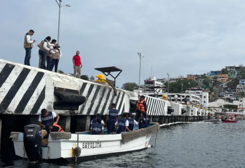 Personal de la Semar realiza labores de limpieza en el muelle turístico de Manzanillo debido a un derrame de hidrocarburo en la zona.
