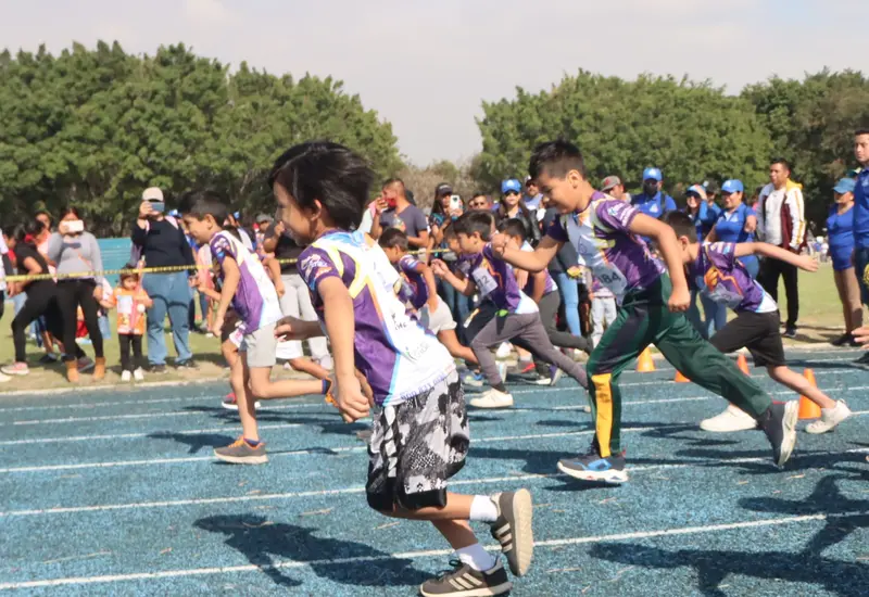 Jóvenes atletas compiten con gran emoción en la pista durante la etapa regional de los Juegos Deportivos Infantiles.