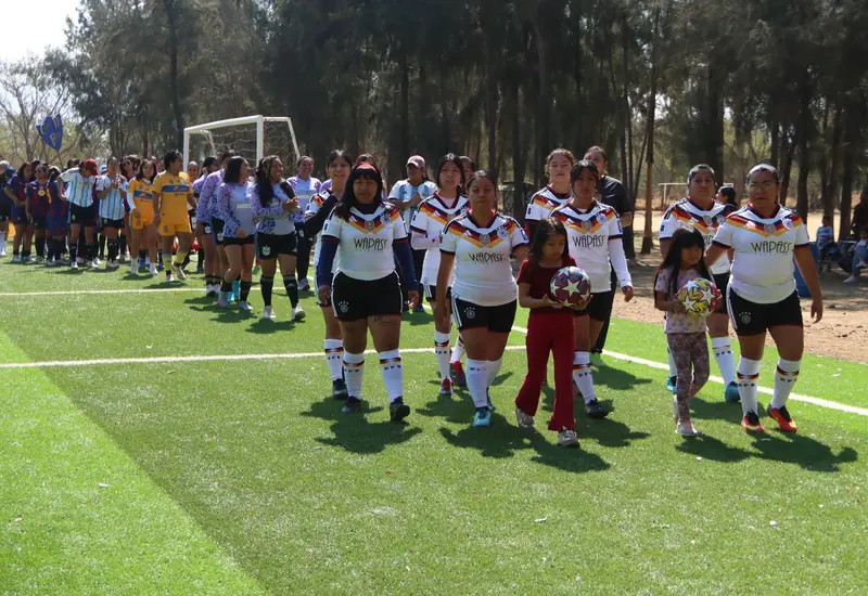 Equipos de la liga de futbol femenil de Zaachila desfilan frente al presídium durante la ceremonia de inauguración del torneo.