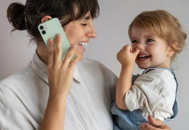 Un niño pequeño se concentra en una pantalla, simbolizando cómo la tecnología puede reemplazar la interacción y presencia de los padres en la infancia.