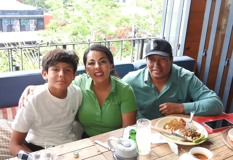 Gener, Saymi y Jesús posan juntos y sonríen para la cámara, compartiendo un momento feliz durante una reunión social.
