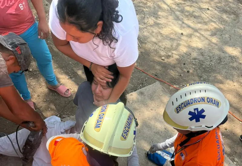 Una joven de 15 años es atendida por paramédicos tras ser rescatada de una letrina donde cayó y se lesionó con una varilla.