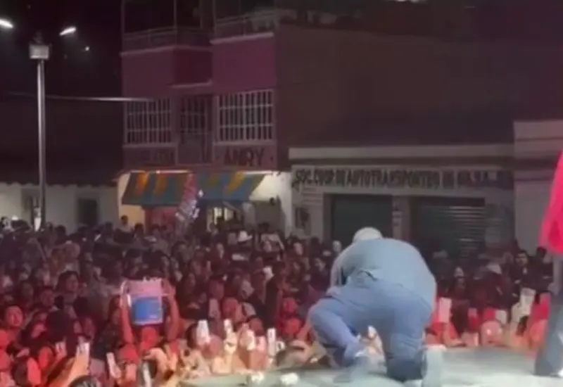 El cantante Lupillo Rivera de pie sobre el escenario usando solo calcetines, después de sufrir el robo de su calzado durante su presentación.